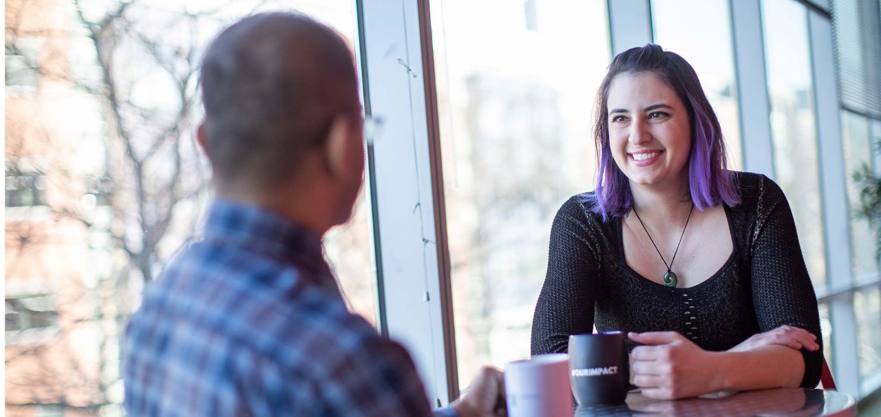 Foto van twee medewerkers die een gesprek hebben