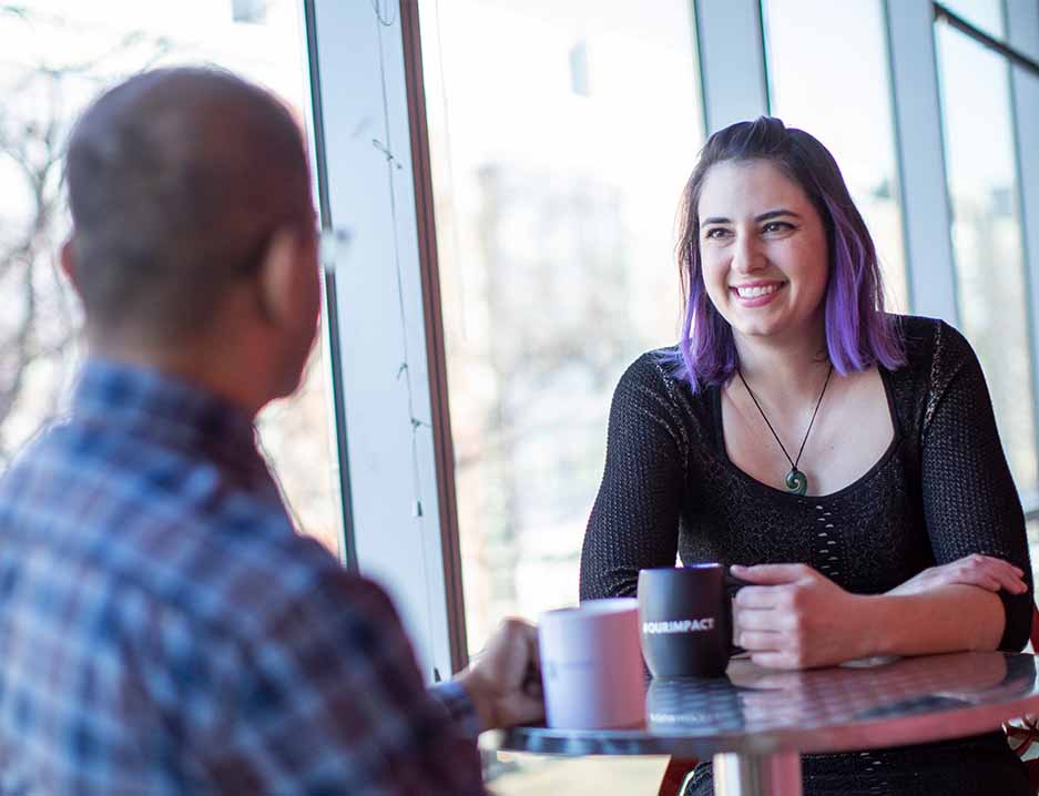 Foto van twee medewerkers die een gesprek hebben